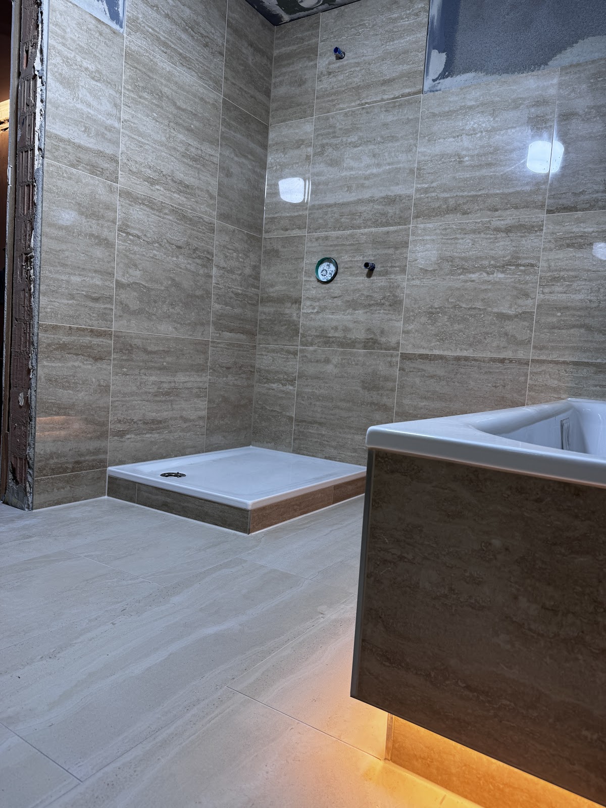 Badezimmer im Rohbauzustand mit großformatigen Fliesen und bodengleicher Dusche, ausgeführt von Fliesen & Vinyl BOGAJ