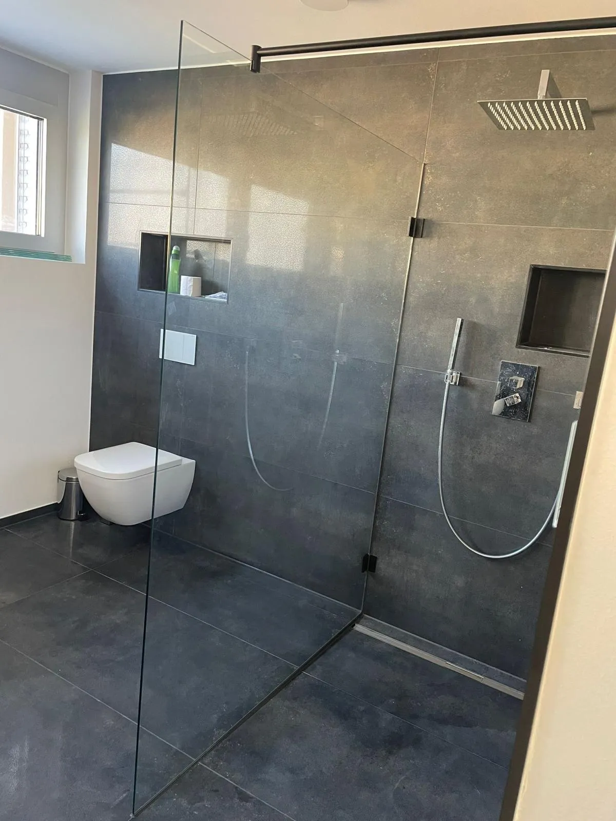 Bad mit bodengleicher Walk-in-Dusche, Wandnischen und dunklen großformatigen Fliesen, ausgeführt von Fliesen & Vinyl BOGAJ
